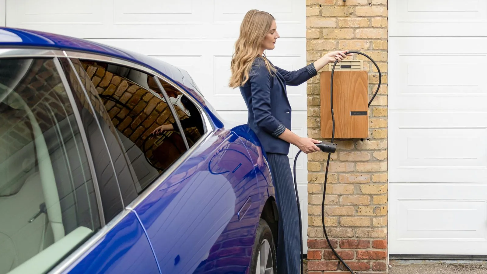 Woman plugging an electric vehicle into a wall-mounted home charger