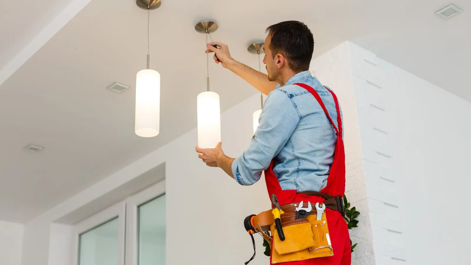 Electrician installing pendant lights on a ceiling